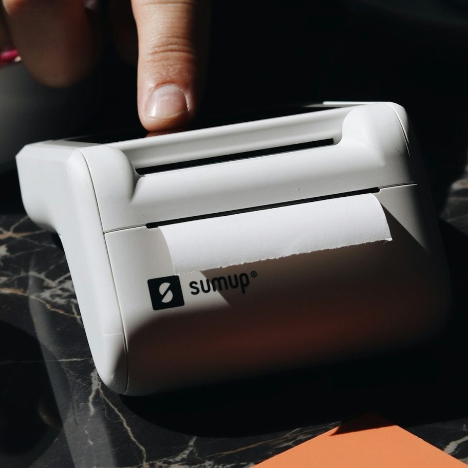Ein kompakter Drucker mit einem weißen Gehäuse und offenem Papierauslass.